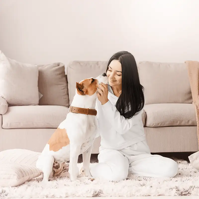 Frau mit Hund auf Teppich sitzend